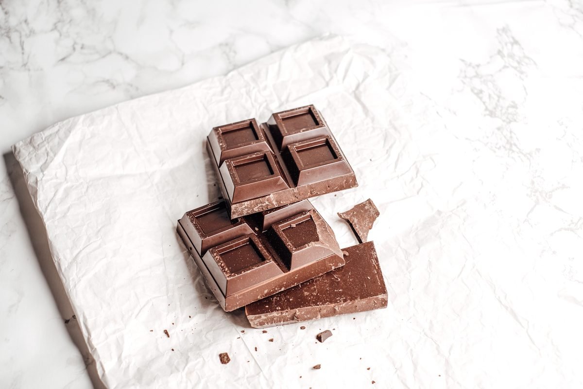 A broken bar of dark chocolate on a white surface