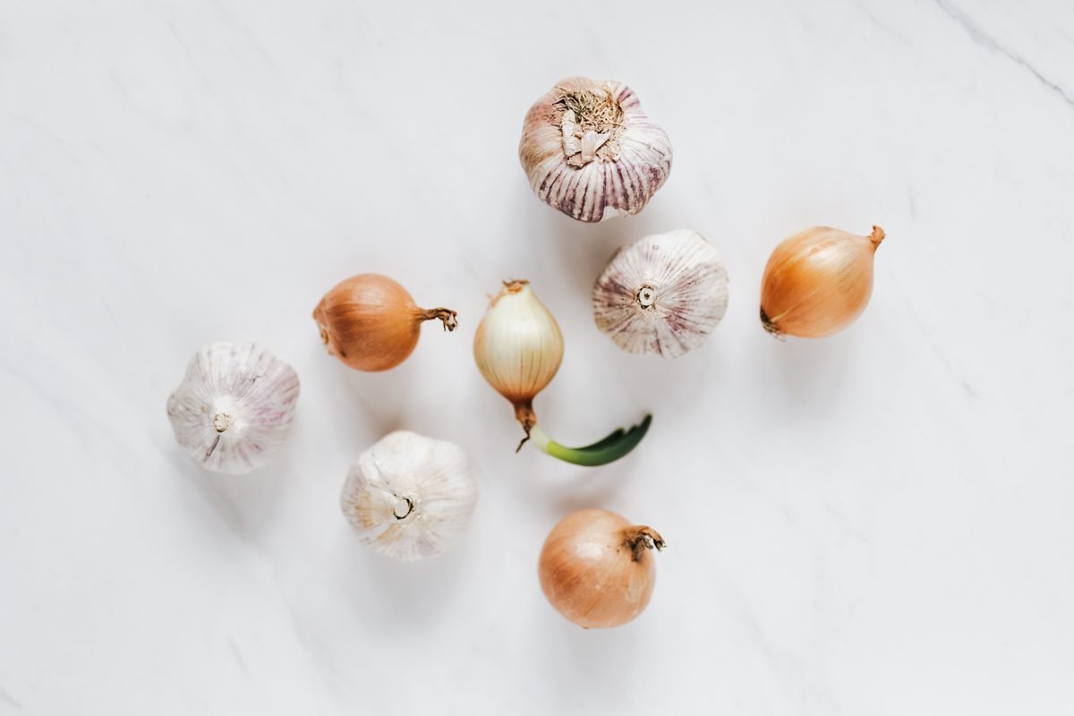 Onions and garlic bulbs arranged on a marble surface